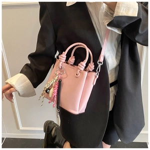 Pink mini bucket bag detail with knotted handle and decorative beaded charm accessory