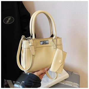 Detail of cream bucket bag showing silver twist lock and mini envelope pouch charm