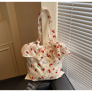 Detail of cherry print shoulder bag with ruffled edges and Magic pocket label