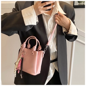 Pink mini bucket bag detail with knotted handles and colorful decorative charms