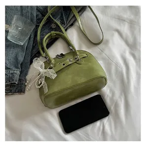 Détail du sac coquillage vert herbe avec nœud en dentelle et perle et accents métalliques