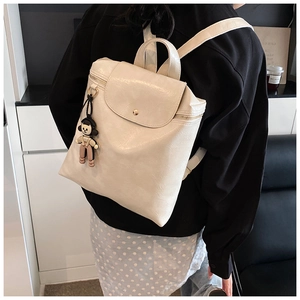 Detail of the cream PU leather backpack with a magnetic flap closure and a cute doll charm
