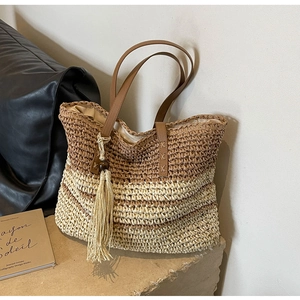 Detail of woven straw tote bag featuring wide brown stripes and a long beaded tassel