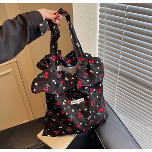 Detail of black floral canvas tote with cherry prints, bow handle, and ruffle trim edges