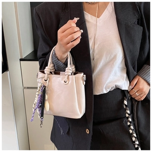 Cream bucket bag with creative keychain and knotted handle shown in a daily lifestyle setting