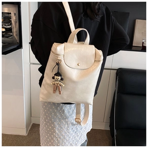Close-up of beige PU leather backpack with magnetic flap closure and cute plush charm