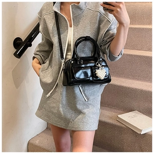 Details der glänzenden schwarzen Boston-Tasche mit Vordertaschen und Perlen-Herz-Anhänger