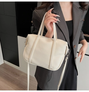 Detail of beige lychee textured leather handbag with silver hardware and adjustable strap