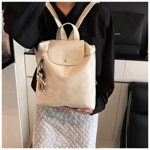 Detail of cream leather backpack featuring soft pleat texture and a cute bear charm