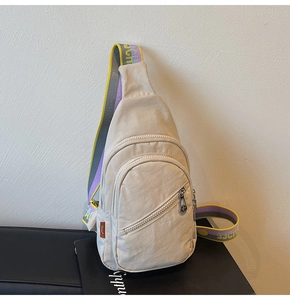 Close-up of beige nylon crossbody bag featuring colorful embroidered shoulder strap detail