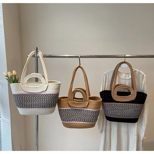 Detailed view of woven tote bags in beige, khaki, and black with double handle design