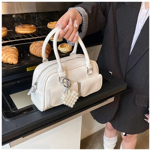 Detail of white wrinkled leather Boston bag with pearl heart charm and front pockets