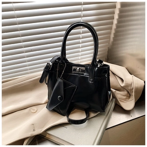 Detail of black patent leather bucket bag with silver lock and small triangle pouch