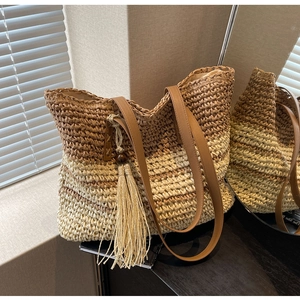 Detail of woven gradient tote bag with tassel charm and faux leather shoulder strap