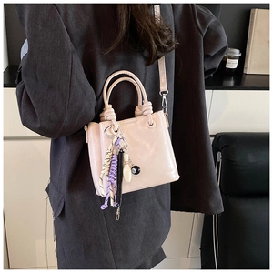 Detail of light pink bucket bag with knotted handles and stylish decorative charms