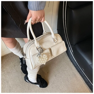 Detailansicht der cremefarbenen Boston Bag mit Faltenoptik, Doppeltaschen und Herzanhänger