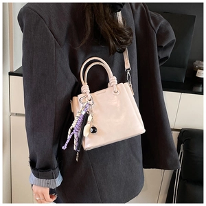 Detail view of cream bucket bag featuring billiards and bowling pins charm accessories
