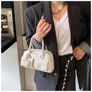Detailansicht einer weißen Boston-Tasche mit Außentaschen und Perlenherz-Anhänger