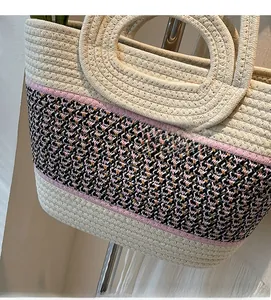 Detail of woven straw tote bag with pink houndstooth pattern and cotton rope texture