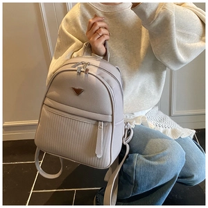 Detailed view of cream leather backpack with pebble texture and embossed stripe pattern