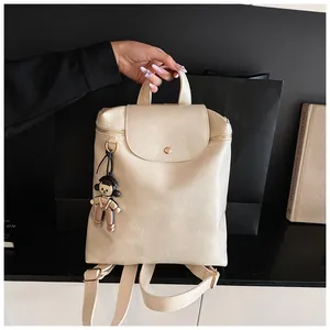 Detail of off-white crinkled PU leather backpack with cute charm and metal buckle