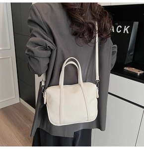 Close-up of beige lychee grain leather texture and metallic hardware on tote bag