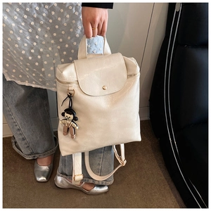 Detail of off-white PU leather backpack with vintage wax texture and cute bear charm