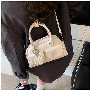 Cream Boston bag with dual pockets and pearl heart charm worn crossbody by a model