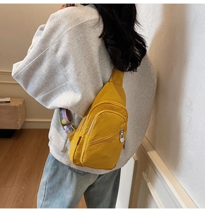 Detail view of yellow nylon chest bag with embroidered sunflower strap on a grey hoodie