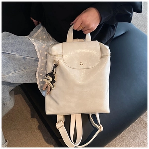 Detailed macro view of cream PU leather backpack featuring metal buckles and side charm
