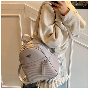 Side view of lavender pebble leather backpack featuring a metal triangle plate and zipper detail