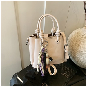Detail of cream bucket bag featuring rope knot handle and creative billiard ball charms
