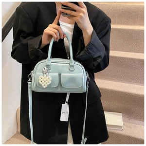 Detail of light blue Boston bag with dual cargo pockets and a pearl heart charm accessory