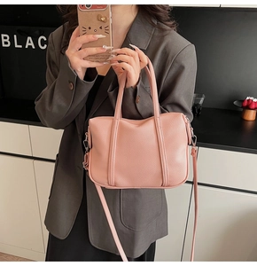 Detail of pink lychee-grain PU leather handbag with silver hooks and adjustable strap