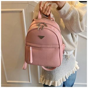 Close-up of pink pebbled leather backpack with triple zippers and triangle metal detail