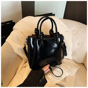 Detail of black glossy patent leather bucket bag with a stylish top knot handle