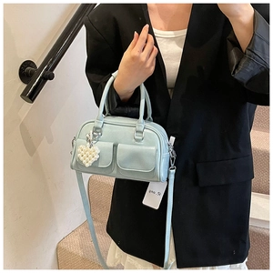 Detail der mintblauen Boston-Tasche mit Herz-Perlenanhänger und Vordertaschen