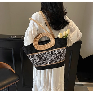 Detail of woven tote bag with round handles, monochrome texture, and shoulder strap