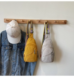 Detail of lightweight nylon chest bags in mustard yellow and grey with wide logo straps