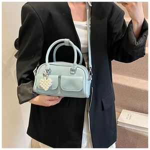 Detail view of light blue Boston bag with heart pearl charm and twin front pockets