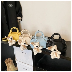 Detail of four small lychee leather handbags with cute dog pendants on a shelf