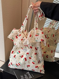 Floral shoulder bag with cherry print and ruffle details in a lifestyle setting