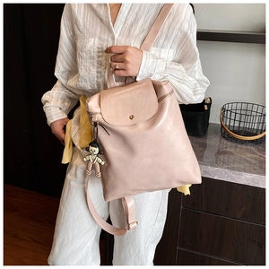 Chic pink leather backpack with flap closure and cute doll charm accessory detail