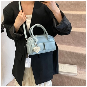 Detail der hellblauen Boston Bag mit Herz-Perlen-Anhänger und Fronttaschenstruktur