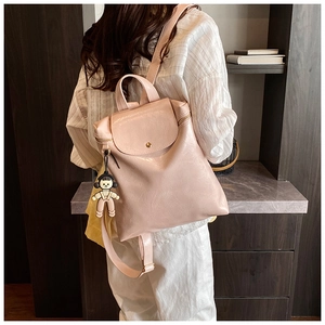 Detail of pink faux leather backpack featuring a side zipper and cute cartoon charm