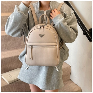 Close-up of beige quilted leather mini backpack featuring triangular metal hardware