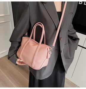 Pink lychee texture handbag with double handles and long shoulder strap on a model