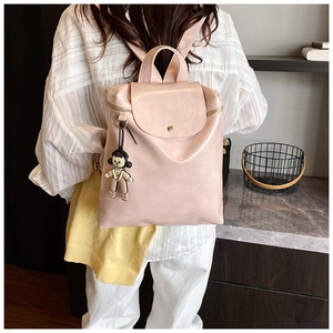 Detail of pink PU leather backpack with gold buckle, side zipper and cartoon pendant