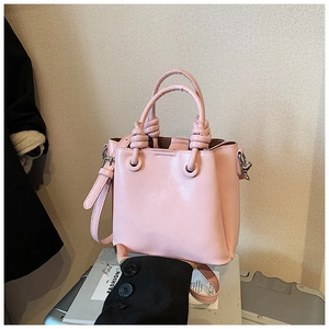 Detail of light pink bucket bag showing knotted handle design and silver metal clasp