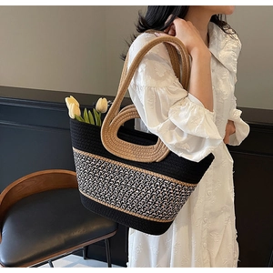 Detail of a large woven tote bag with contrast handles and houndstooth texture